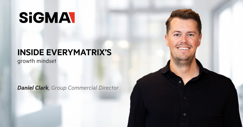 image with a blurry background of an office building, with an image of Daniel Clark on the right, SiGMA logo on the left, and the text: Inside EveryMatrix’s growth mindset